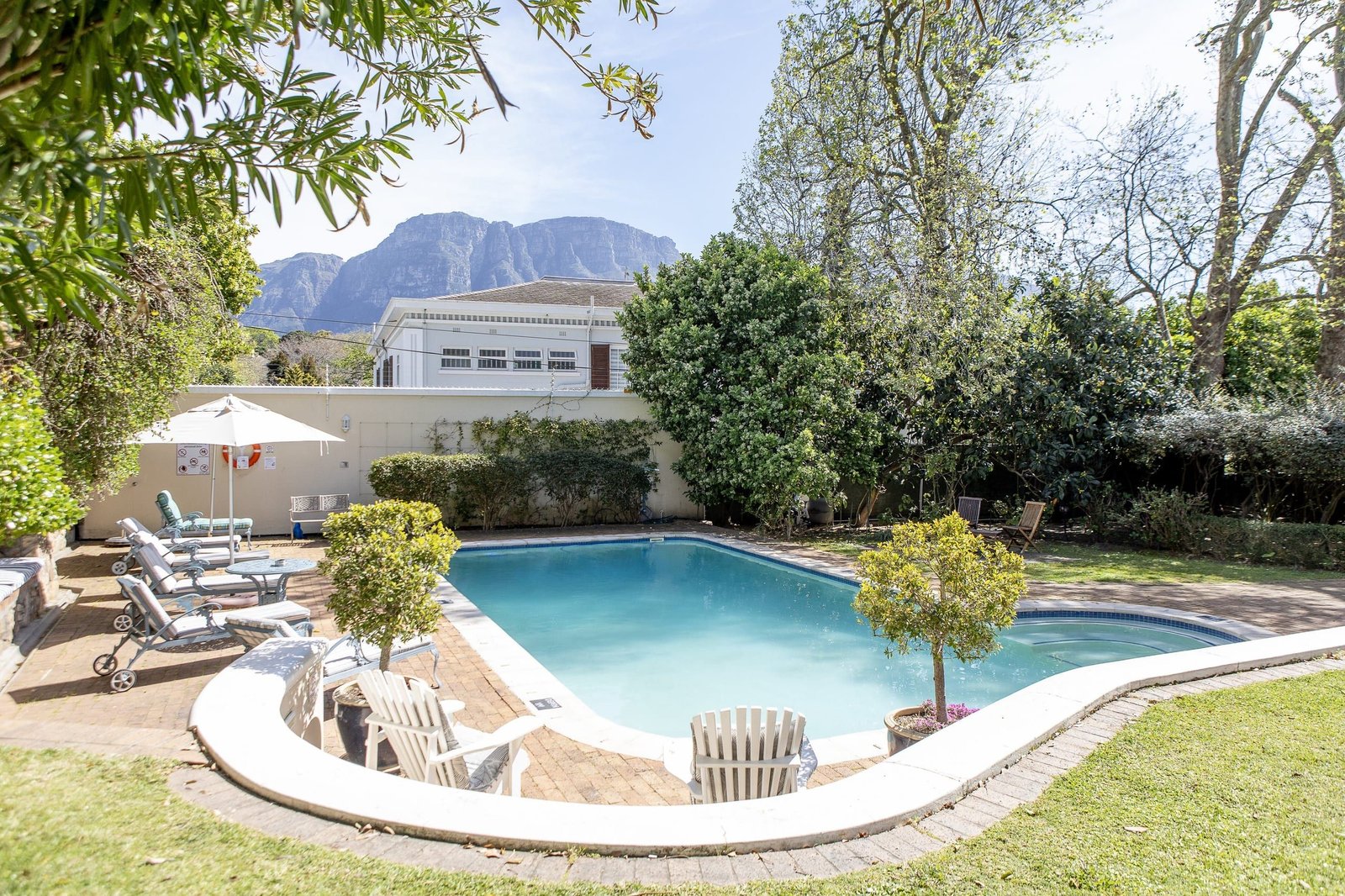 The pool and loungers in the garden, with the mountain rising beyond the garden wall.